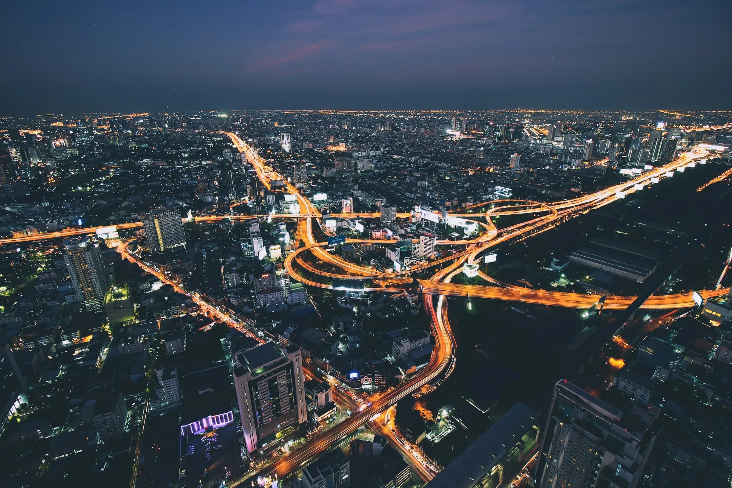 An interconnected city at dusk, with illuminated roads linking its buildings